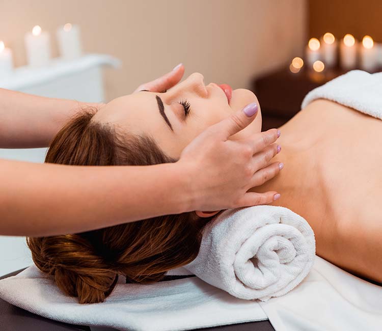 Side view of young woman having facial massage in spa salon