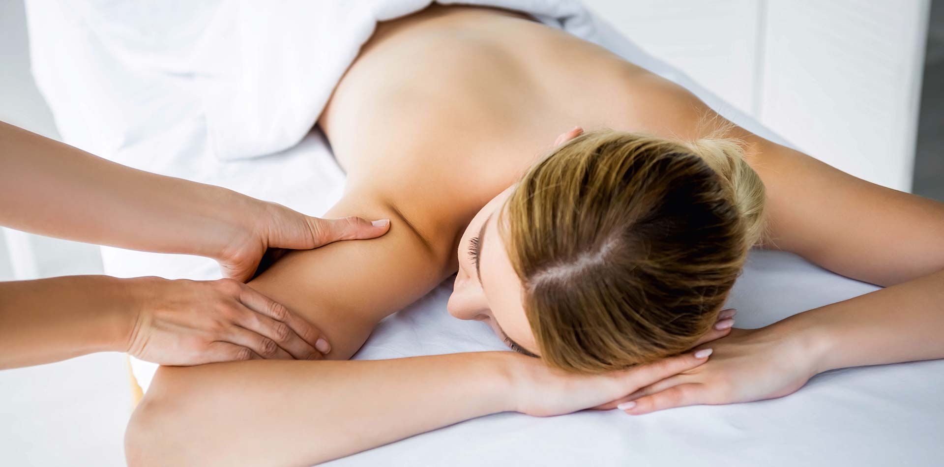 Cropped view of masseur doing back massage to woman in spa