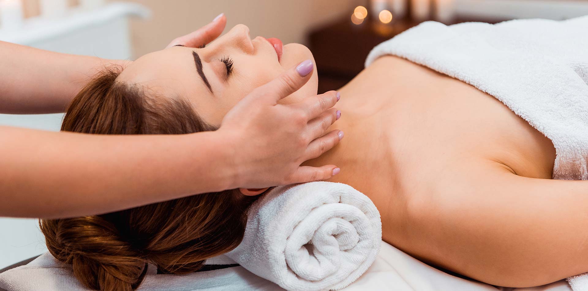 Side view of young woman having facial massage in spa salon