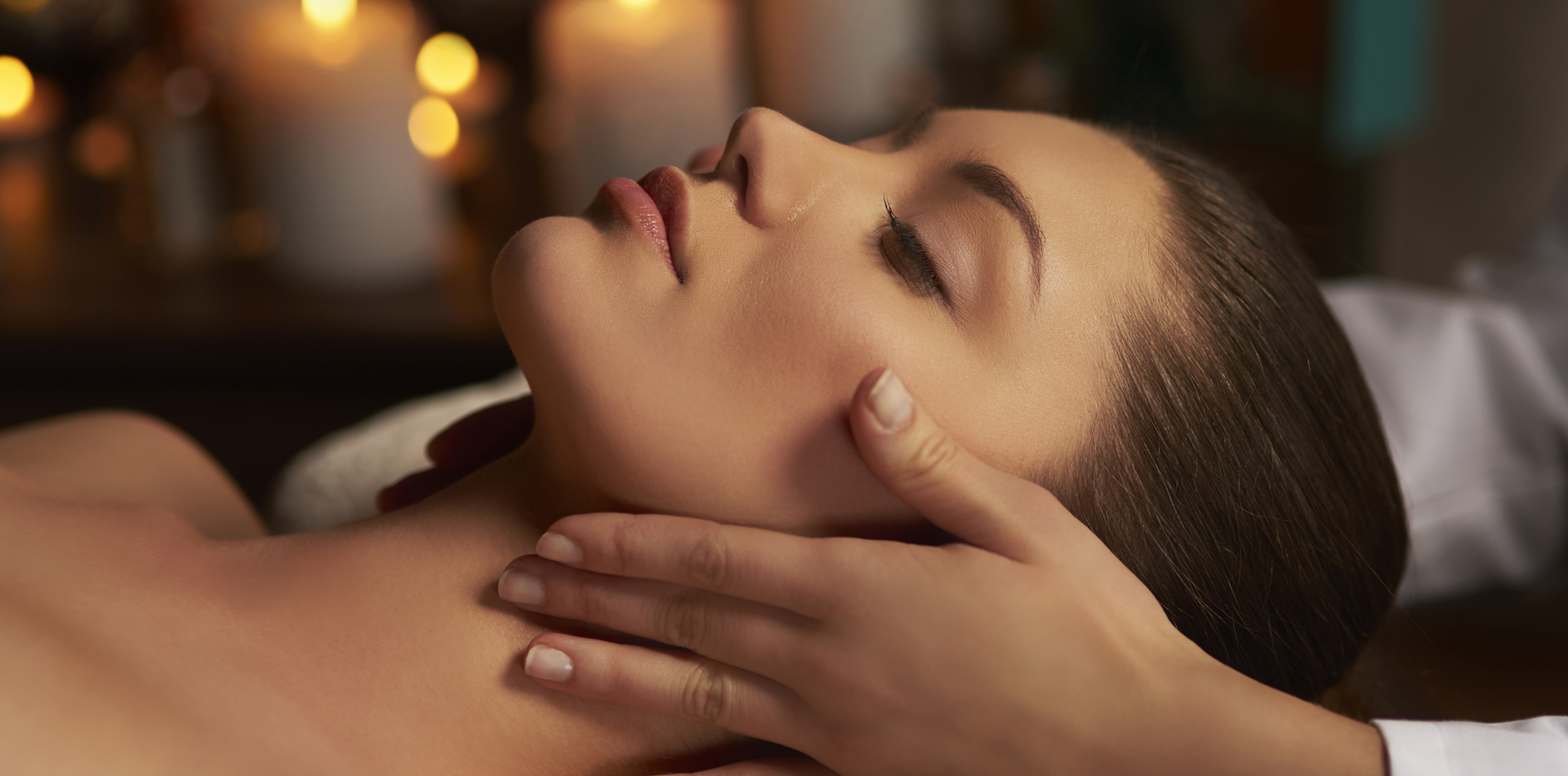 Side view of young woman having facial massage in spa salon